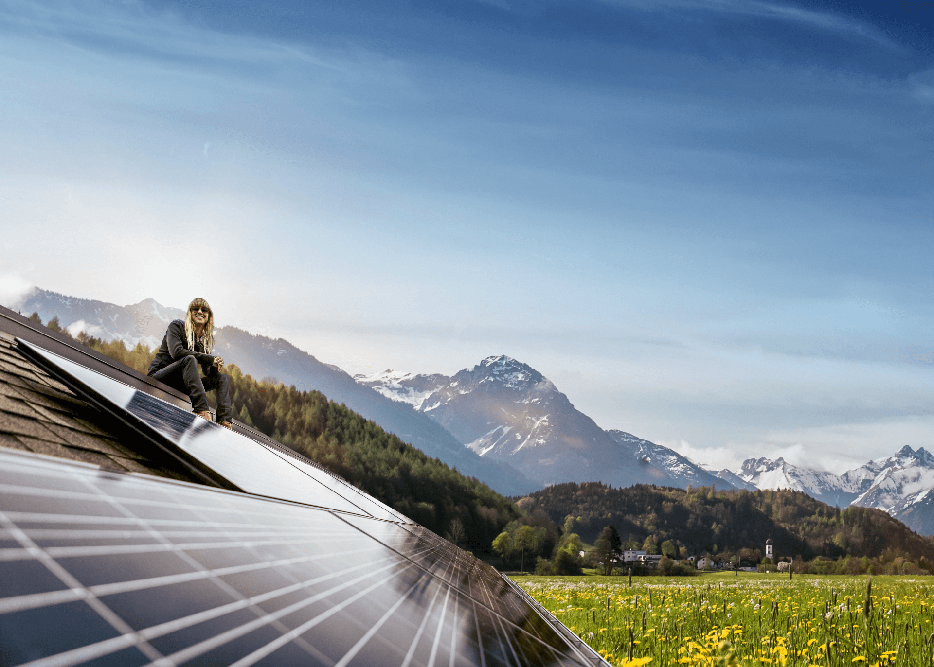 Frau sitzt auf Dach mit PV-Anlage