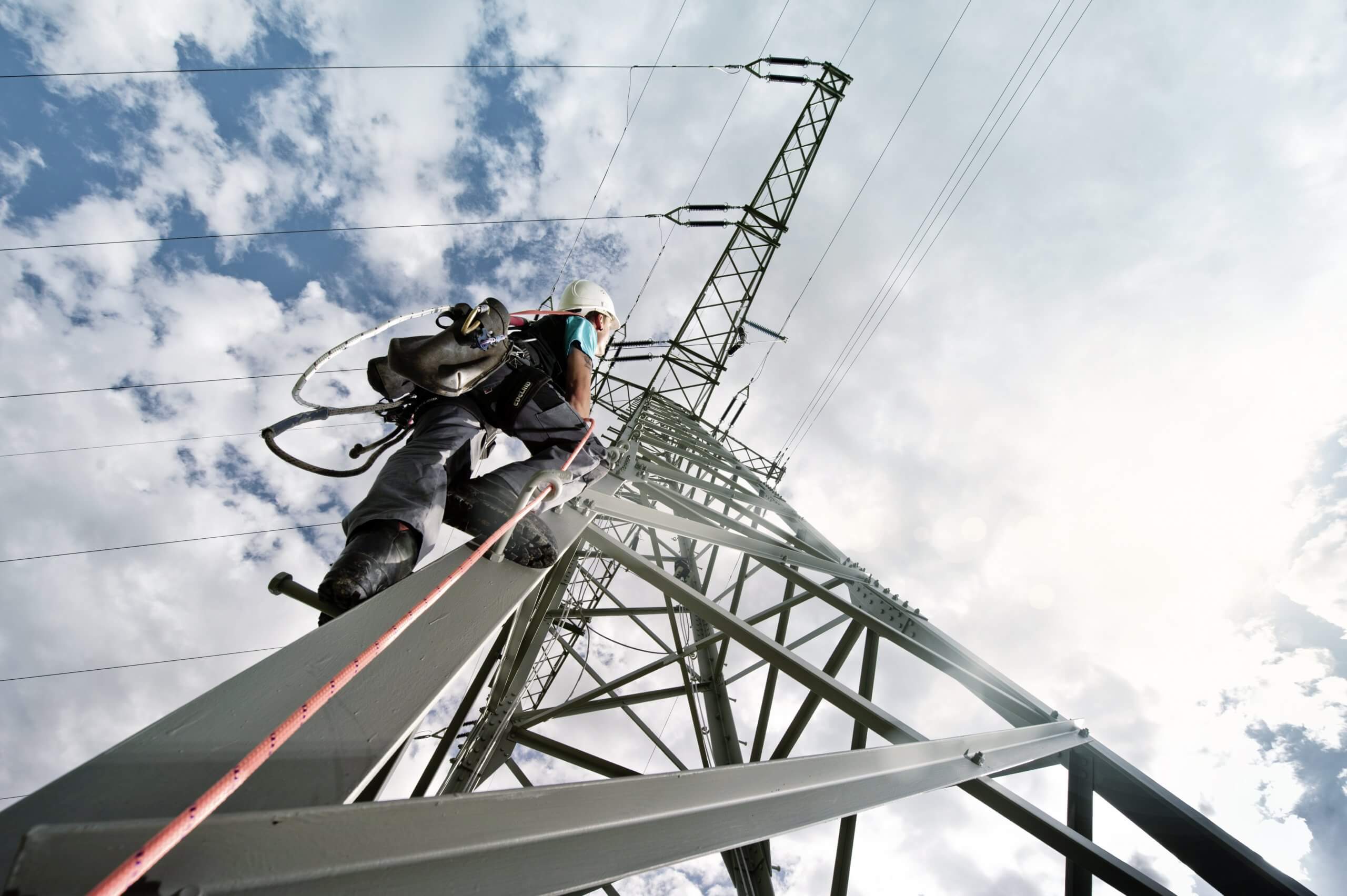 Elektriker klettert Hochspannungsmast hoch