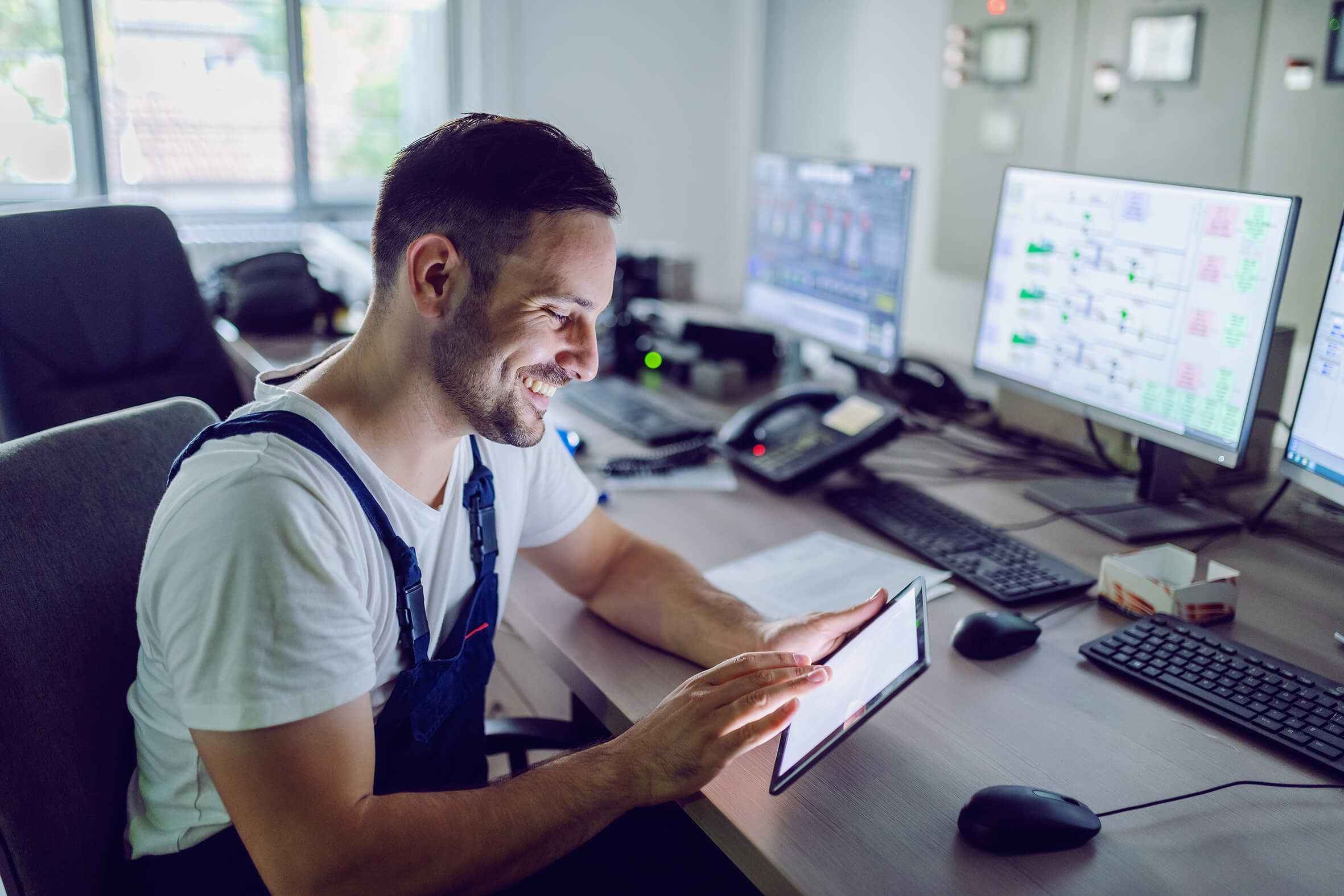 Mitarbeiter am Schreibtisch mit Tablet in der Hand
