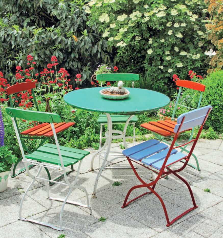 Fünf bunte Gartenstühle an einem runden Tisch