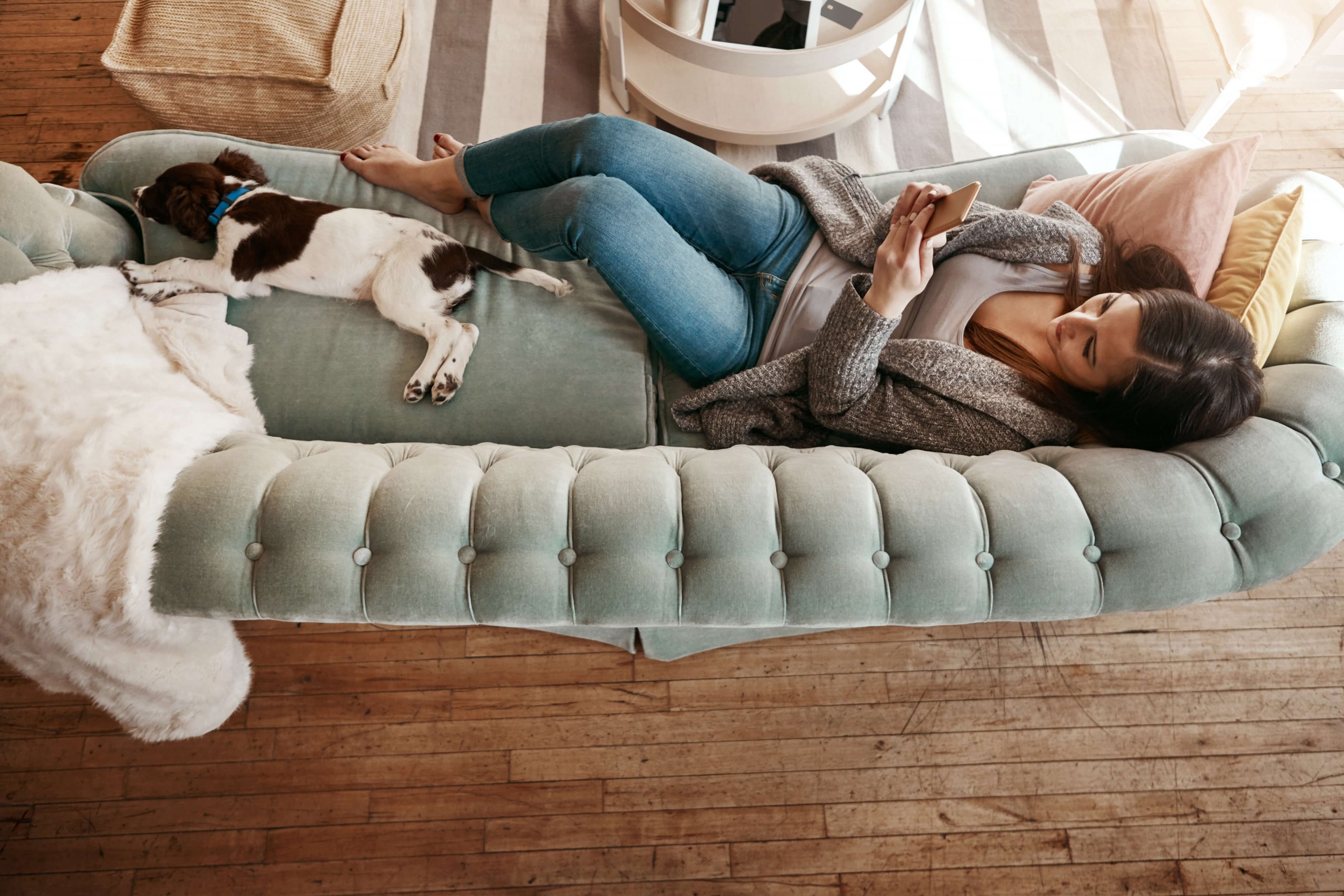 Frau liegt mit Hund auf Sofa