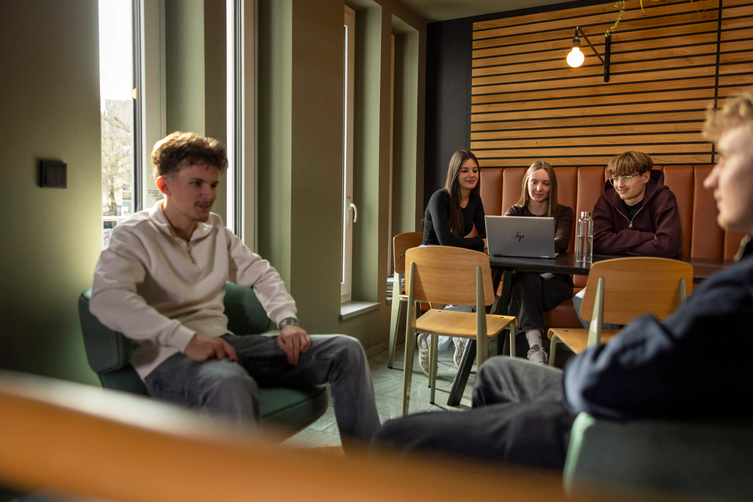 Eine Gruppe Auszubildender in einem Café am Laptop