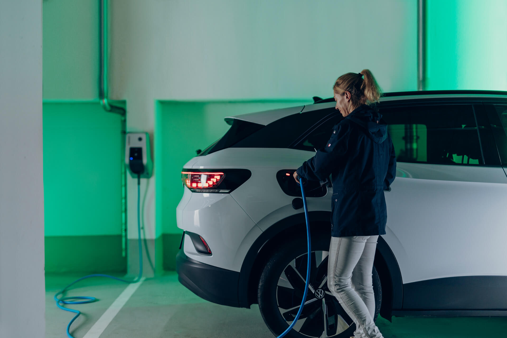 Frau lädt in Tiefgarage E-Auto auf