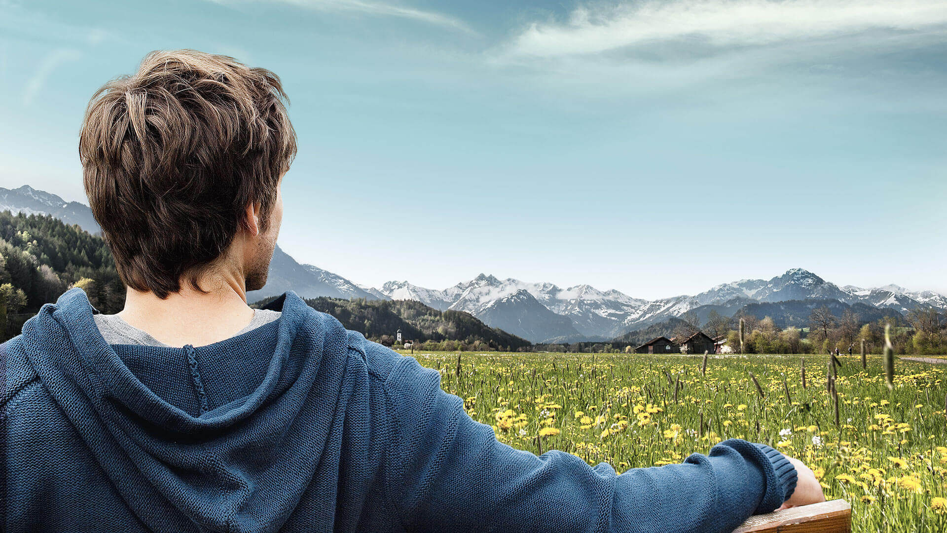 Mann sitzt auf einer Bank an einem Feld